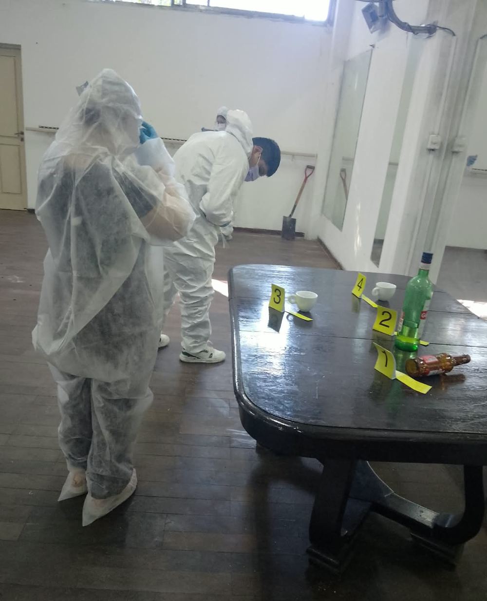 Alumnos con trajes de protección señalizando indicios numerados sobre una mesa durante una práctica